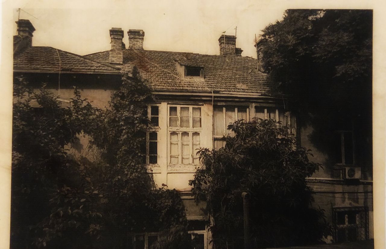 A sepia-toned vintage photograph of an old building with trees.
